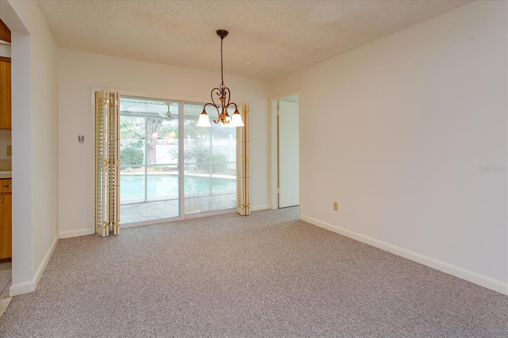 A carpeted dining area features a hanging light fixture and sliding glass doors to a pool — 1192 LADY SUSAN DRIVE, CASSELBERRY, FL
