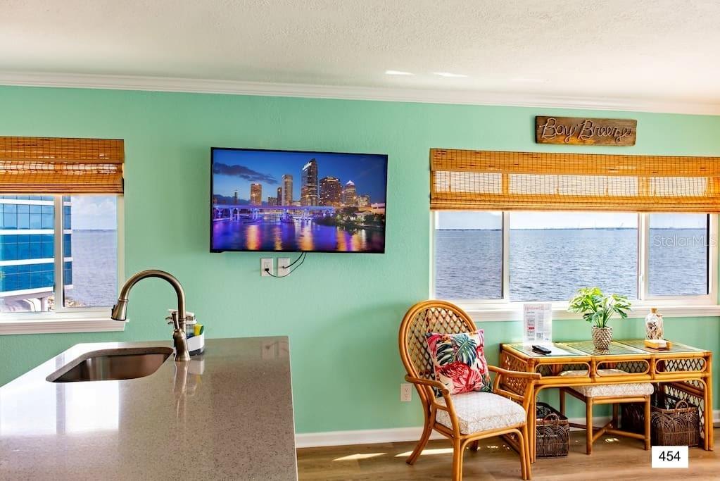 A kitchen island with a sink faces a wall-mounted television and a window overlooking water — 2506 N ROCKY POINT DRIVE UNIT 454, TAMPA, FL