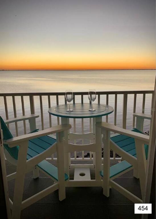A balcony features a small round table with two chairs overlooking a sunset over water — 2506 N ROCKY POINT DRIVE UNIT 454, TAMPA, FL