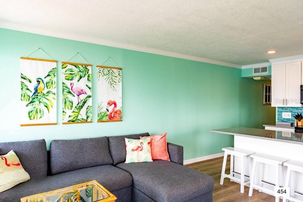 A living room with a gray sectional sofa, mint green walls, and tropical wall art — 2506 N ROCKY POINT DRIVE UNIT 454, TAMPA, FL
