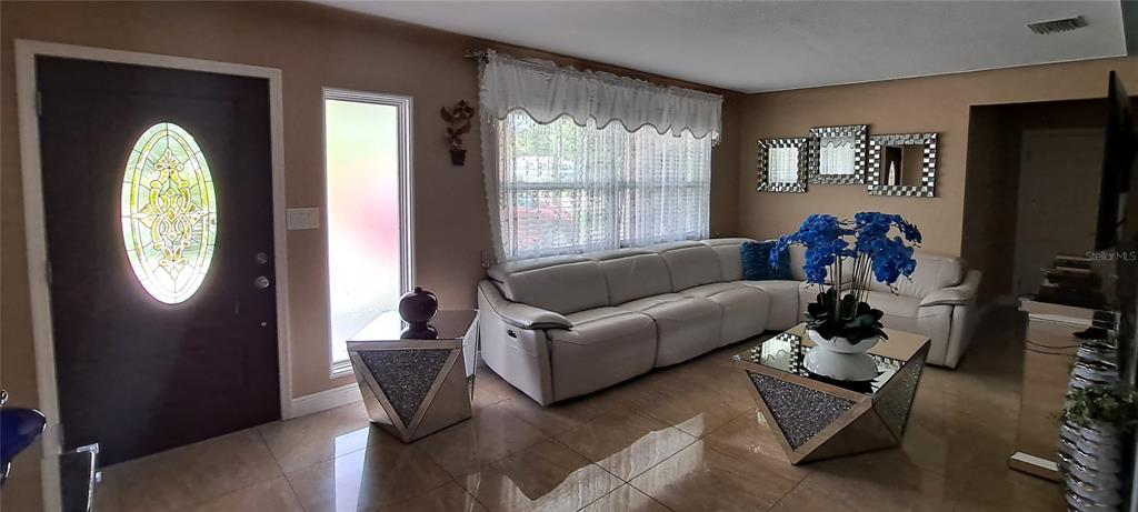 A living room features a white sectional sofa, mirrored tables, and tile flooring — 3964 22ND AVENUE N, ST PETERSBURG, FL