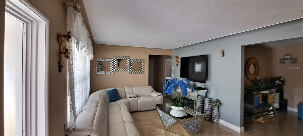 A living room features a white sectional sofa, a mirrored coffee table, and a television — 3964 22ND AVENUE N, ST PETERSBURG, FL