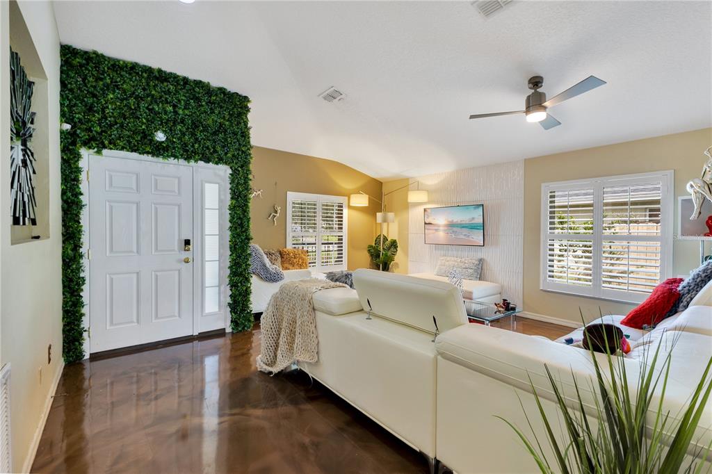 A living room features a white sectional sofa, a green wall accent, and glossy flooring — 2717 EAGLE CANYON DRIVE S, KISSIMMEE, FL