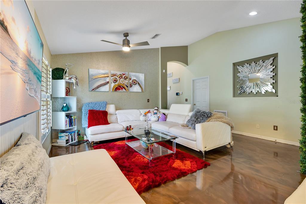 A living room features a white sectional sofa, a red area rug, and wall art — 2717 EAGLE CANYON DRIVE S, KISSIMMEE, FL