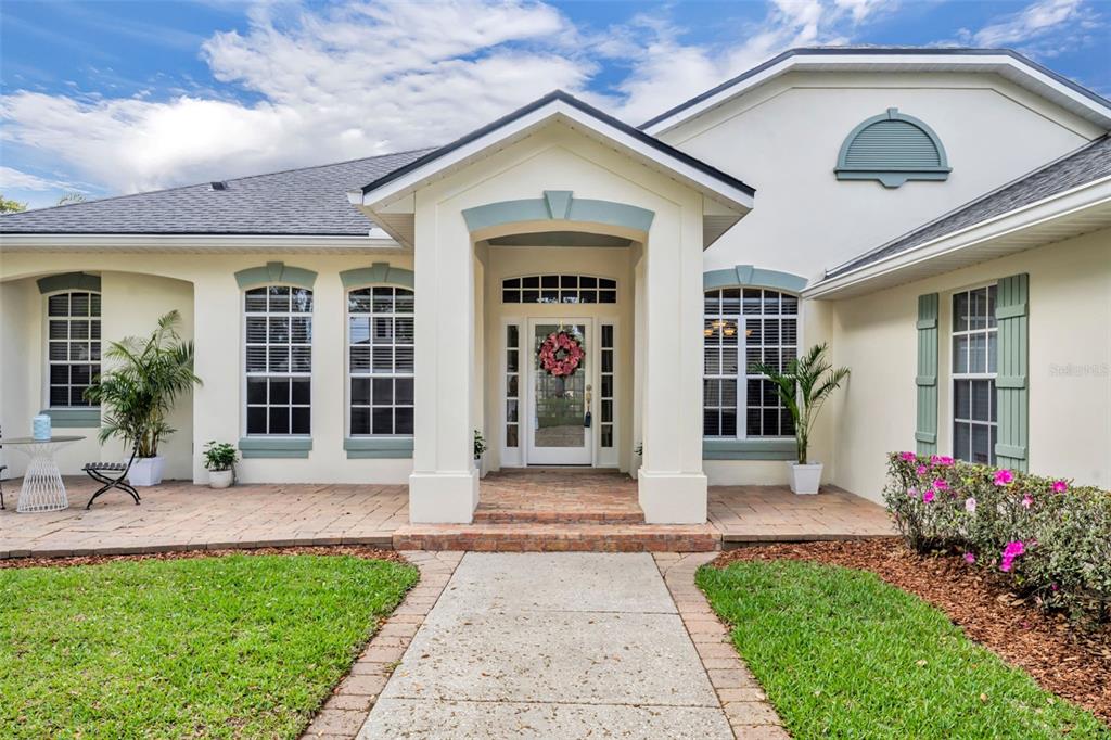 A front view of a single-story house with a paved walkway, porch, and arched windows — 1800 MAGNOLIA AVENUE, WINTER PARK, FL