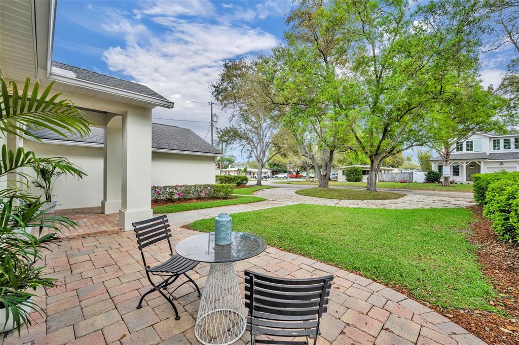 A paved patio with a small table and two chairs overlooks a grassy front yard — 1800 MAGNOLIA AVENUE, WINTER PARK, FL