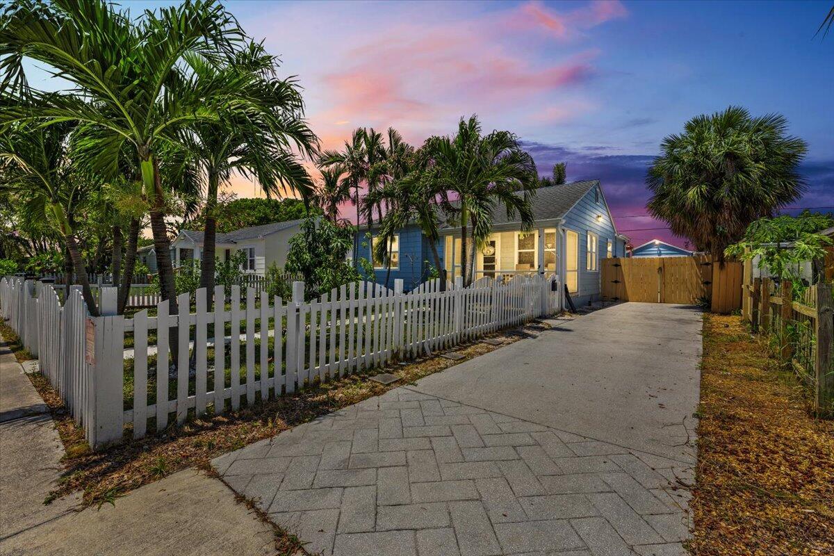 A blue house with a white picket fence and a paved driveway at sunset — 915 N K Street, FL 33460, FL