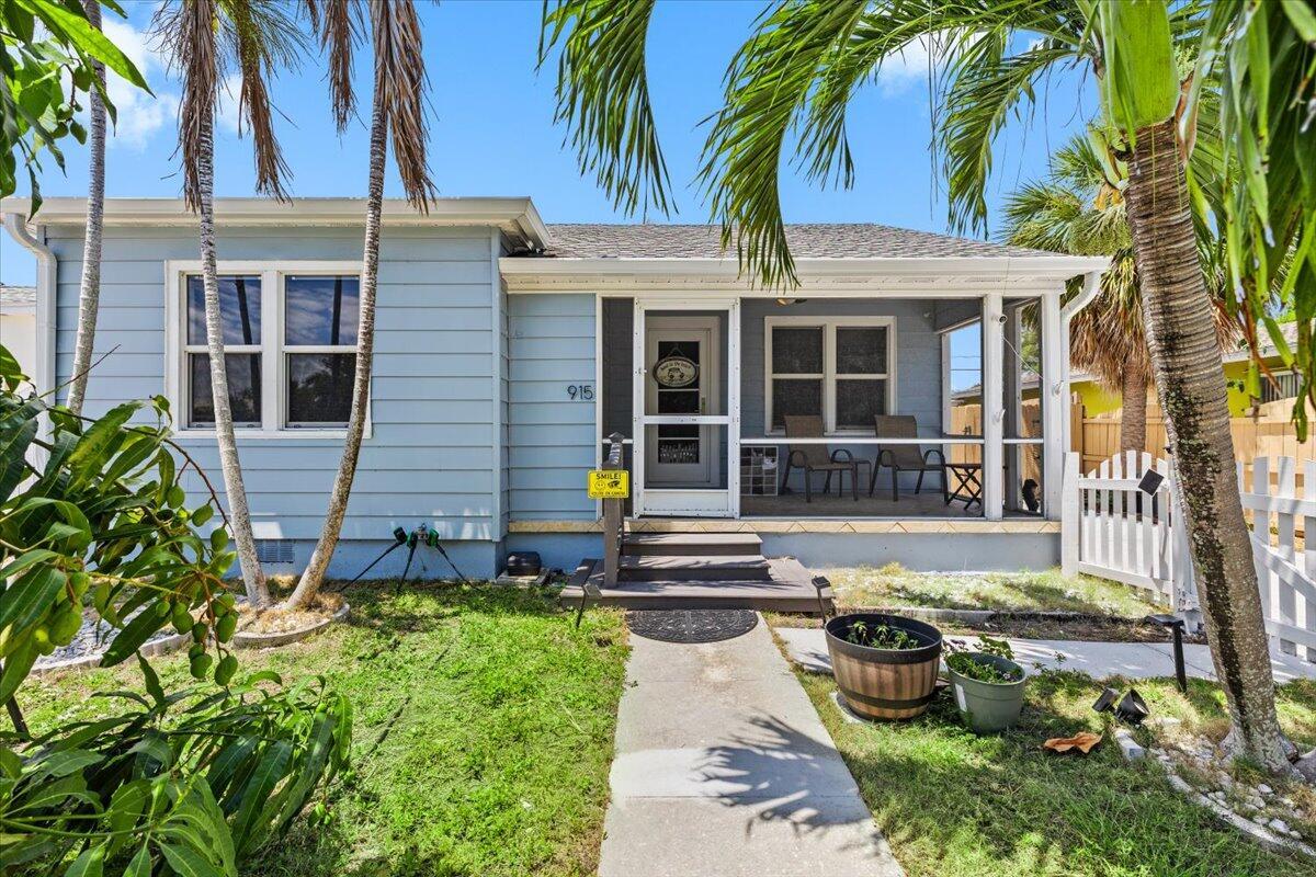 A light blue house with a screened-in front porch and a concrete walkway — 915 N K Street, FL 33460, FL