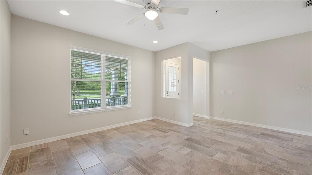 A bright room with light-colored walls, tile flooring, a ceiling fan, and a large window — 8744 DUFFERIN LANE, ORLANDO, FL