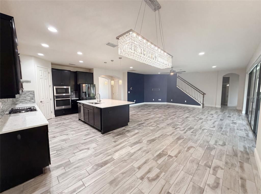 A kitchen with dark cabinets and a white island opens into a large living area — 21797 BRISKE MORNING AVENUE, LAND O LAKES, FL