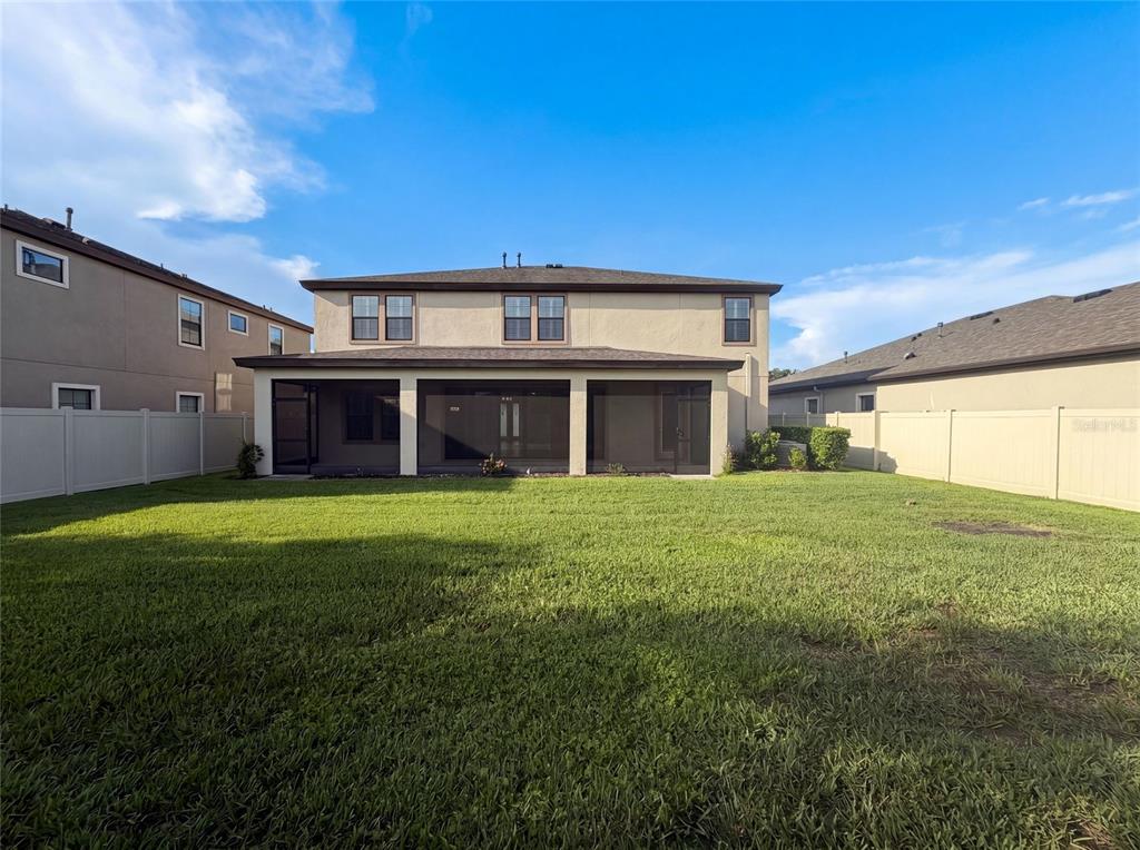 A two-story house with a screened-in patio and a fenced backyard under a blue sky — 21797 BRISKE MORNING AVENUE, LAND O LAKES, FL