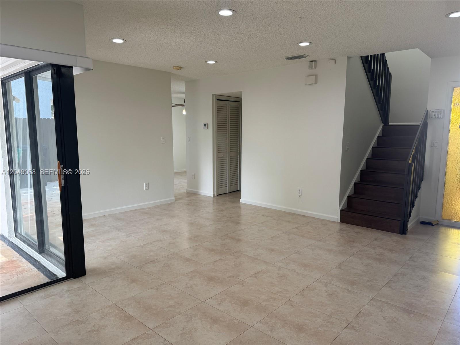 A living area features tile flooring, recessed lighting, a staircase, and a sliding glass door — 15054 SW 127th Pl # 0, Miami FL 33186, MIAMI, FL