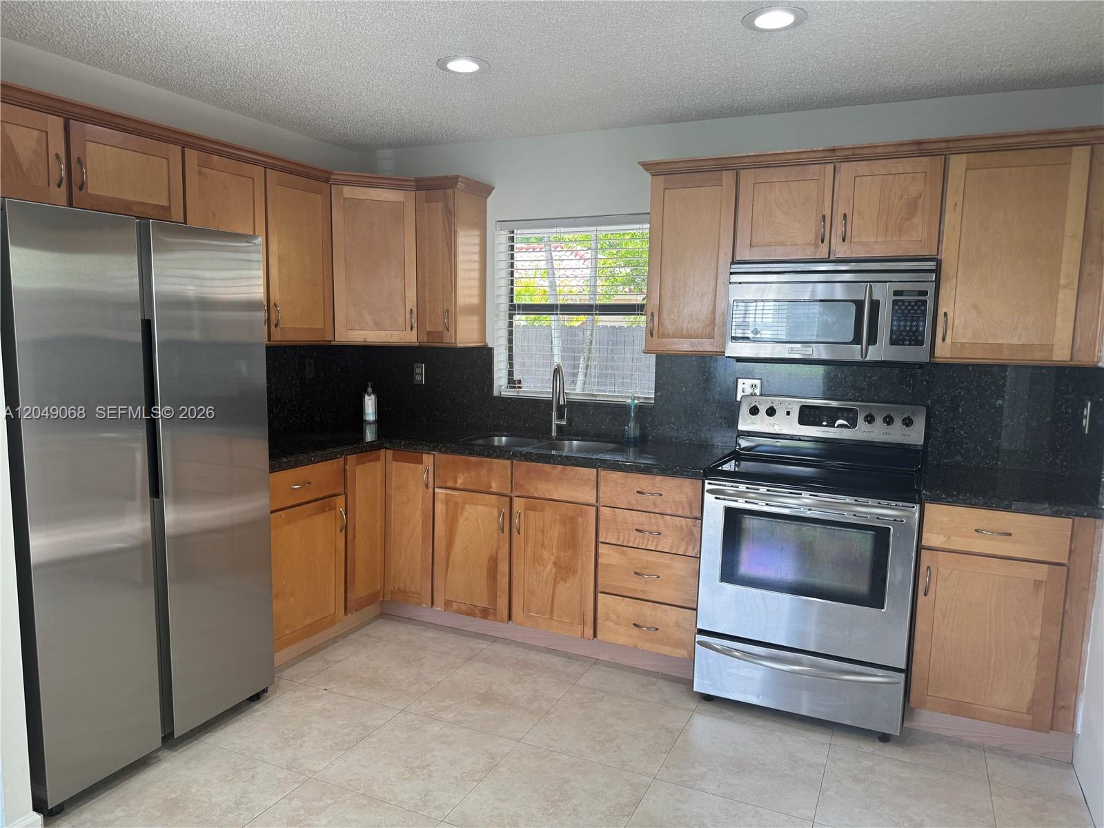 A kitchen features wood cabinets, stainless steel appliances, and dark granite countertops — 15054 SW 127th Pl # 0, Miami FL 33186, MIAMI, FL