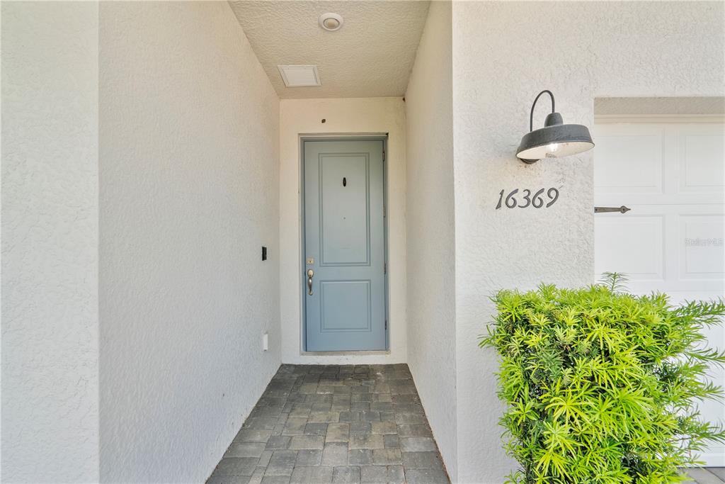 A light blue front door is set in a recessed entryway with stone pavers — 16369 PALMETTO STREET, PUNTA GORDA, FL