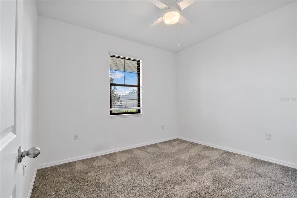 An empty bedroom features white walls, gray carpet, a ceiling fan, and a single window — 16369 PALMETTO STREET, PUNTA GORDA, FL
