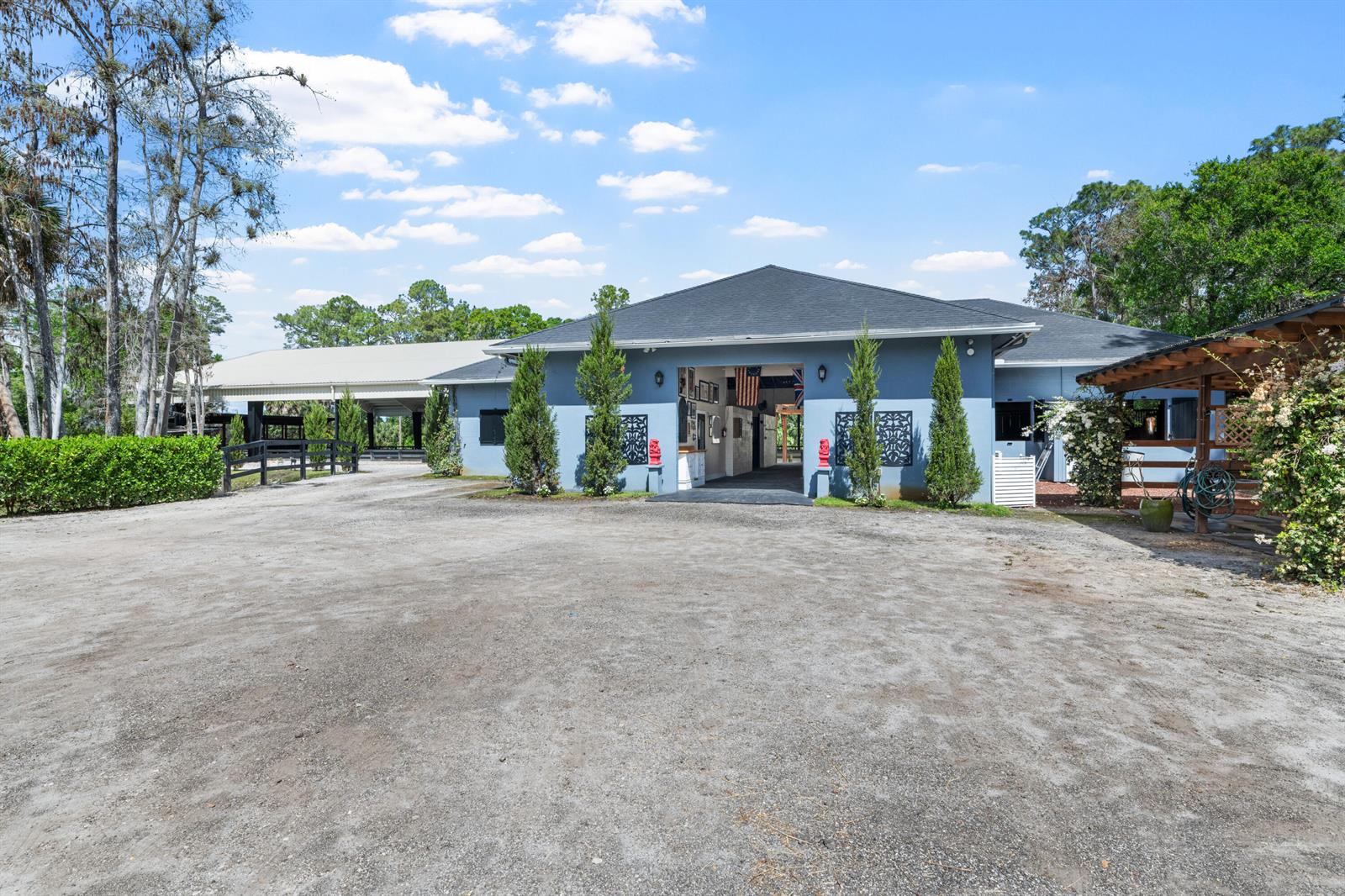 A blue barn with a central breezeway stands on a large dirt lot — 15161 Collecting Canal Road, FL 33470, FL