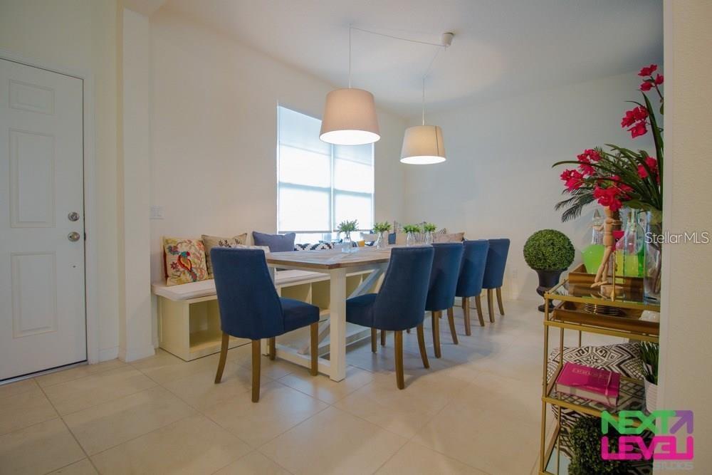 A dining room features a wooden table with blue chairs, a bench, and two pendant lights — 3809 MT VERNON WAY, KISSIMMEE, FL