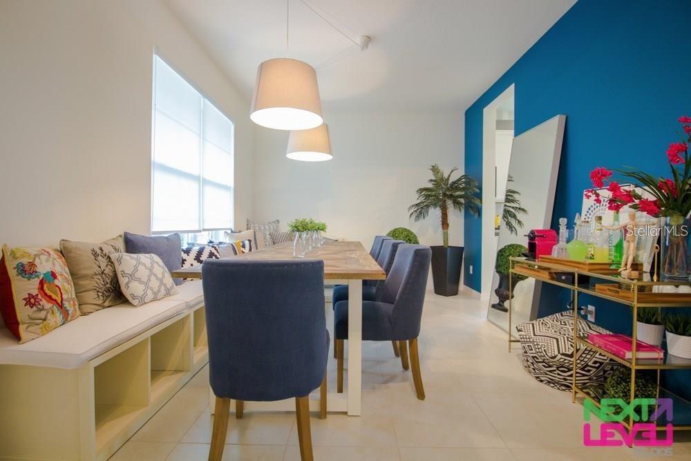 A dining room features a long wooden table, blue upholstered chairs, and a built-in bench — 3809 MT VERNON WAY, KISSIMMEE, FL