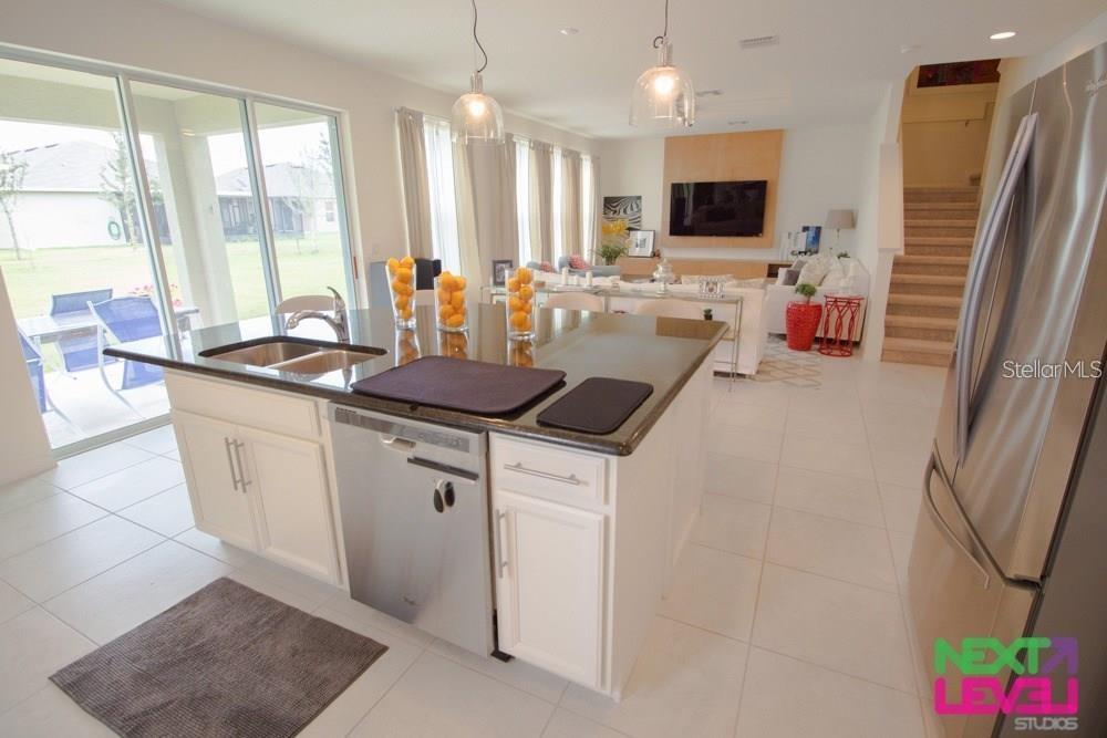 A kitchen island with a sink and dishwasher overlooks a living area with stairs — 3809 MT VERNON WAY, KISSIMMEE, FL
