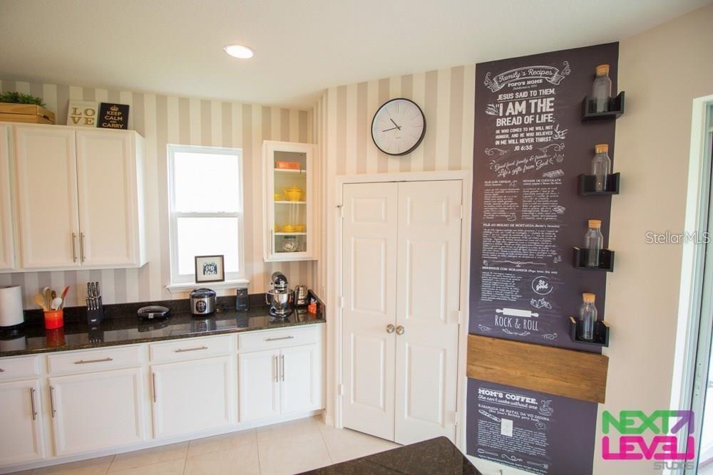 A kitchen features white cabinets, dark granite countertops, striped wallpaper, and a decorative chalkboard wall — 3809 MT VERNON WAY, KISSIMMEE, FL