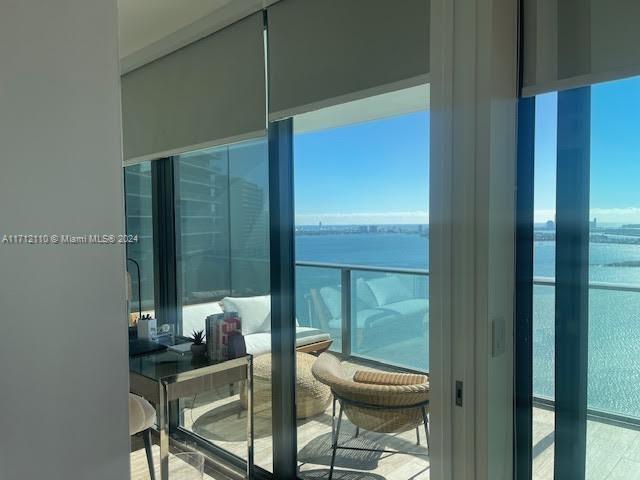 A room with a desk and chair overlooks a balcony with water views and city skyline — 650 NE 32nd St # 3606, Miami FL 33137, MIAMI, FL