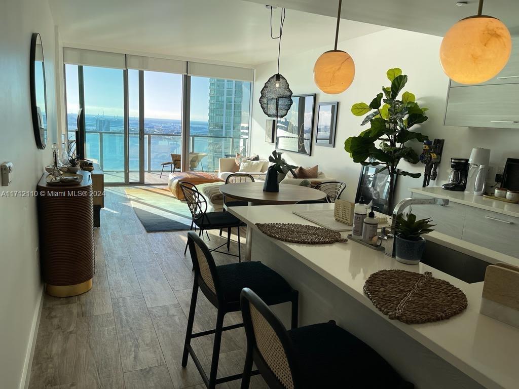 An open-concept living and dining area features a kitchen island, modern lighting, and balcony views — 650 NE 32nd St # 3606, Miami FL 33137, MIAMI, FL