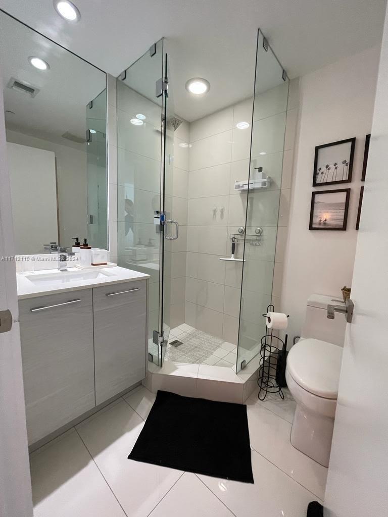 A modern bathroom features a glass-enclosed corner shower, a vanity with a sink, and tile flooring — 650 NE 32nd St # 3606, Miami FL 33137, MIAMI, FL