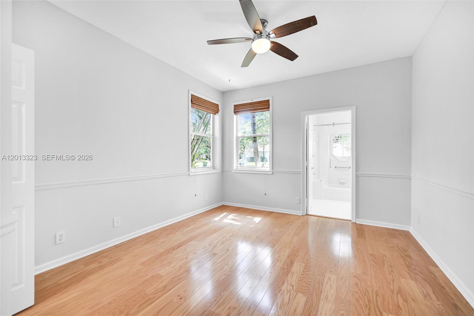 An empty bedroom features light gray walls, hardwood floors, a ceiling fan, and an attached bathroom — 2553 Bay Pointe Drive, Weston FL 33327, WESTON, FL