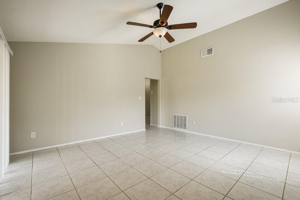An empty room with light-colored tile flooring, vaulted ceilings, and a ceiling fan — 1000 DINERO DRIVE, WINTER SPRINGS, FL