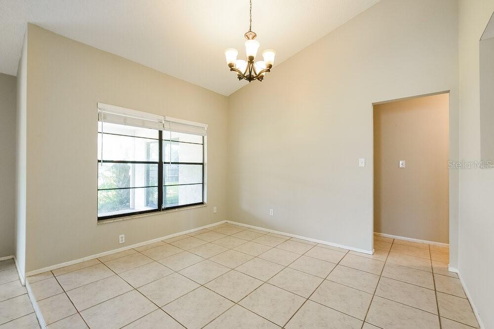 A dining room with beige walls, tile flooring, a vaulted ceiling, and a chandelier — 1000 DINERO DRIVE, WINTER SPRINGS, FL