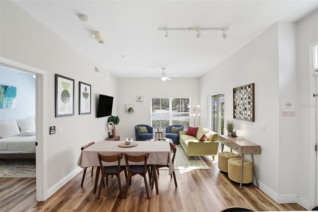 A living and dining area with wood-look flooring, a light green sofa, and blue chairs — 2606 LODI CIRCLE UNIT 102, KISSIMMEE, FL