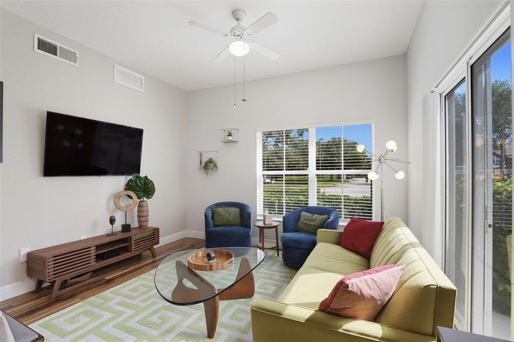 A living room features a green sofa, two blue armchairs, a glass coffee table, and a television — 2606 LODI CIRCLE UNIT 102, KISSIMMEE, FL