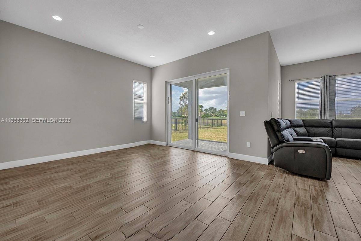 A living room features light gray walls, wood-look tile flooring, and a sliding glass door — 4655 Citron Way, Westlake FL 33470, WESTLAKE, FL