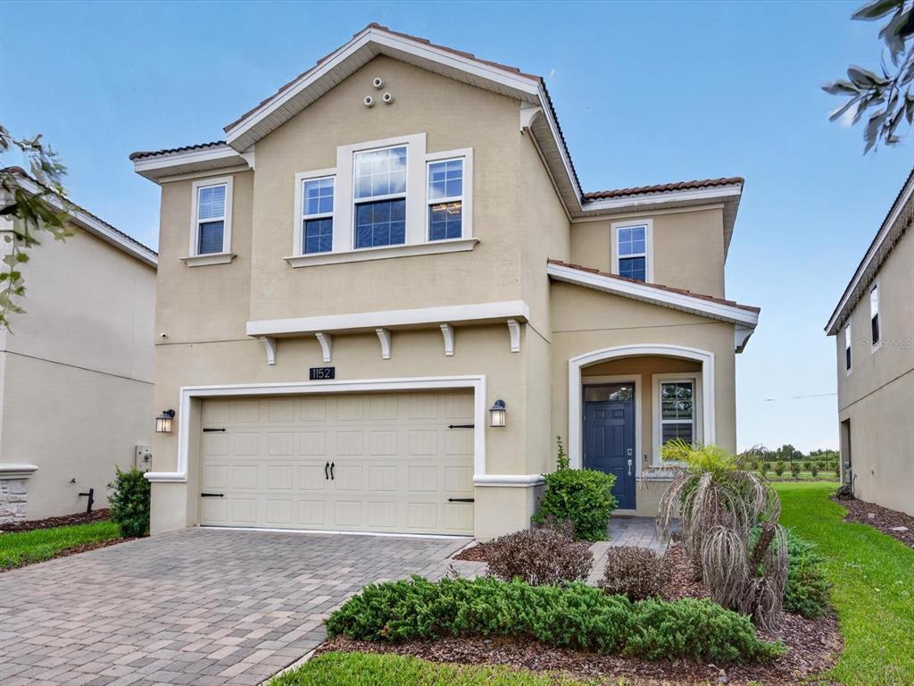 A two-story tan stucco house with a two-car garage and a paved driveway — 1152 TRAPPERS TRAIL LOOP, DAVENPORT, FL