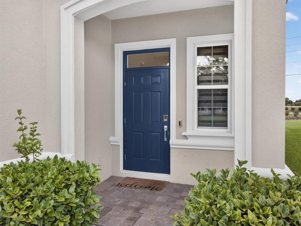 A blue front door with a transom window sits beside a window on a porch — 1152 TRAPPERS TRAIL LOOP, DAVENPORT, FL