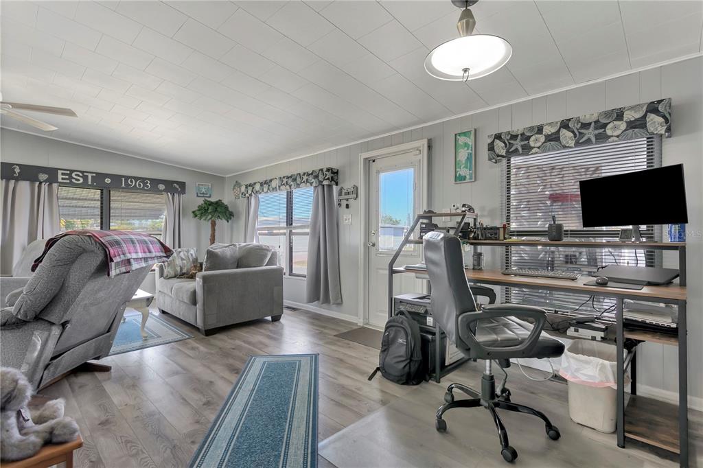 A living room features wood-look flooring, a desk area, a recliner, and a sofa — 5127 8TH STREET W, BRADENTON, FL