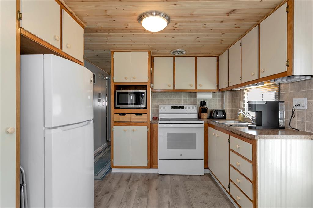A kitchen with white appliances, wooden cabinets, and a light wood-paneled ceiling — 5127 8TH STREET W, BRADENTON, FL