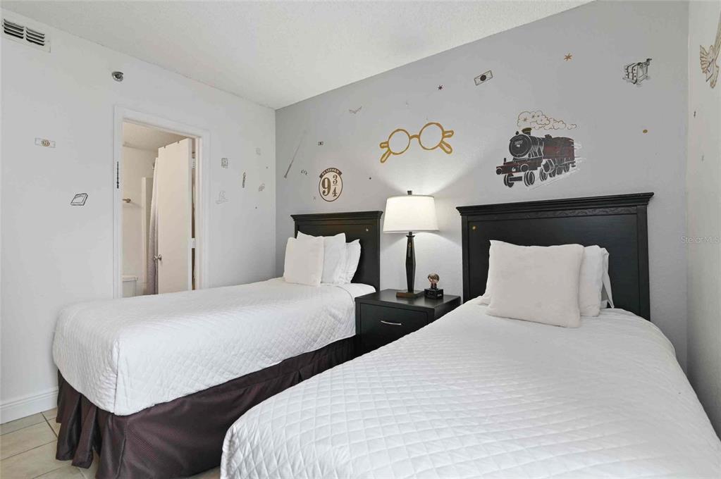 A bedroom features two twin beds with white bedding and Harry Potter-themed wall decals — 6165 CARRIER DRIVE UNIT 1402, ORLANDO, FL
