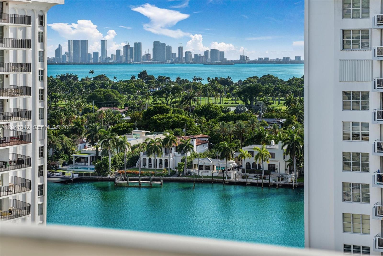 An elevated view shows a waterfront residential area with palm trees and a city skyline — 5701 Collins Ave # 1415, Miami Beach FL 33140, MIAMI BEACH, FL