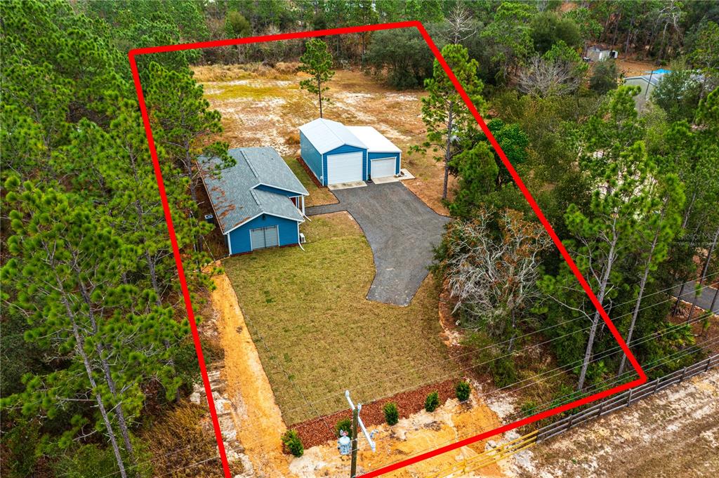 An aerial view shows a blue house and a detached garage on a wooded lot — 11751 NE 105TH AVENUE, ARCHER, FL