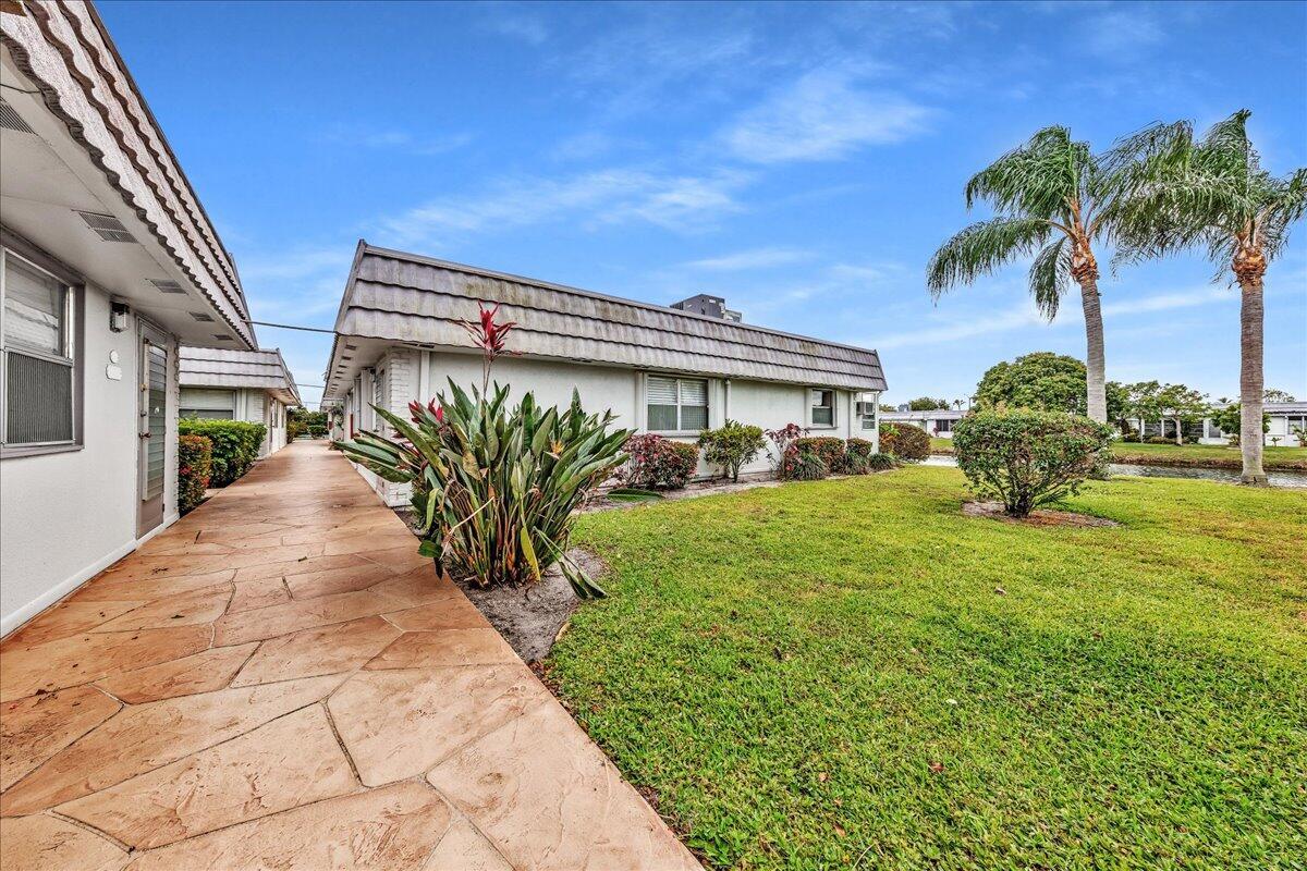 A stone walkway leads past a single-story building with a sloped roof and palm trees — 150 Valencia Boulevard # G, Delray Beach FL 33446, DELRAY BEACH, FL