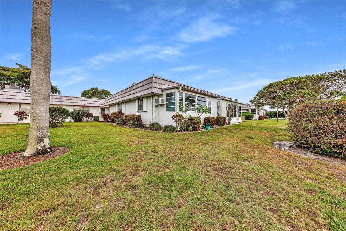 A low-rise residential building with a tiled roof sits on a grassy lawn — 150 Valencia Boulevard # G, Delray Beach FL 33446, DELRAY BEACH, FL