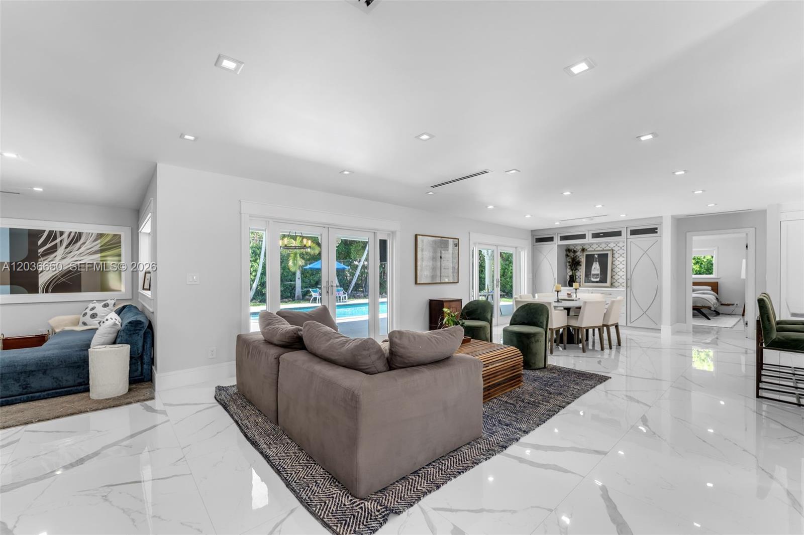 A spacious living and dining area features white marble floors, modern furniture, and glass doors — 6561 Marlin Dr, Coral Gables FL 33158, CORAL GABLES, FL