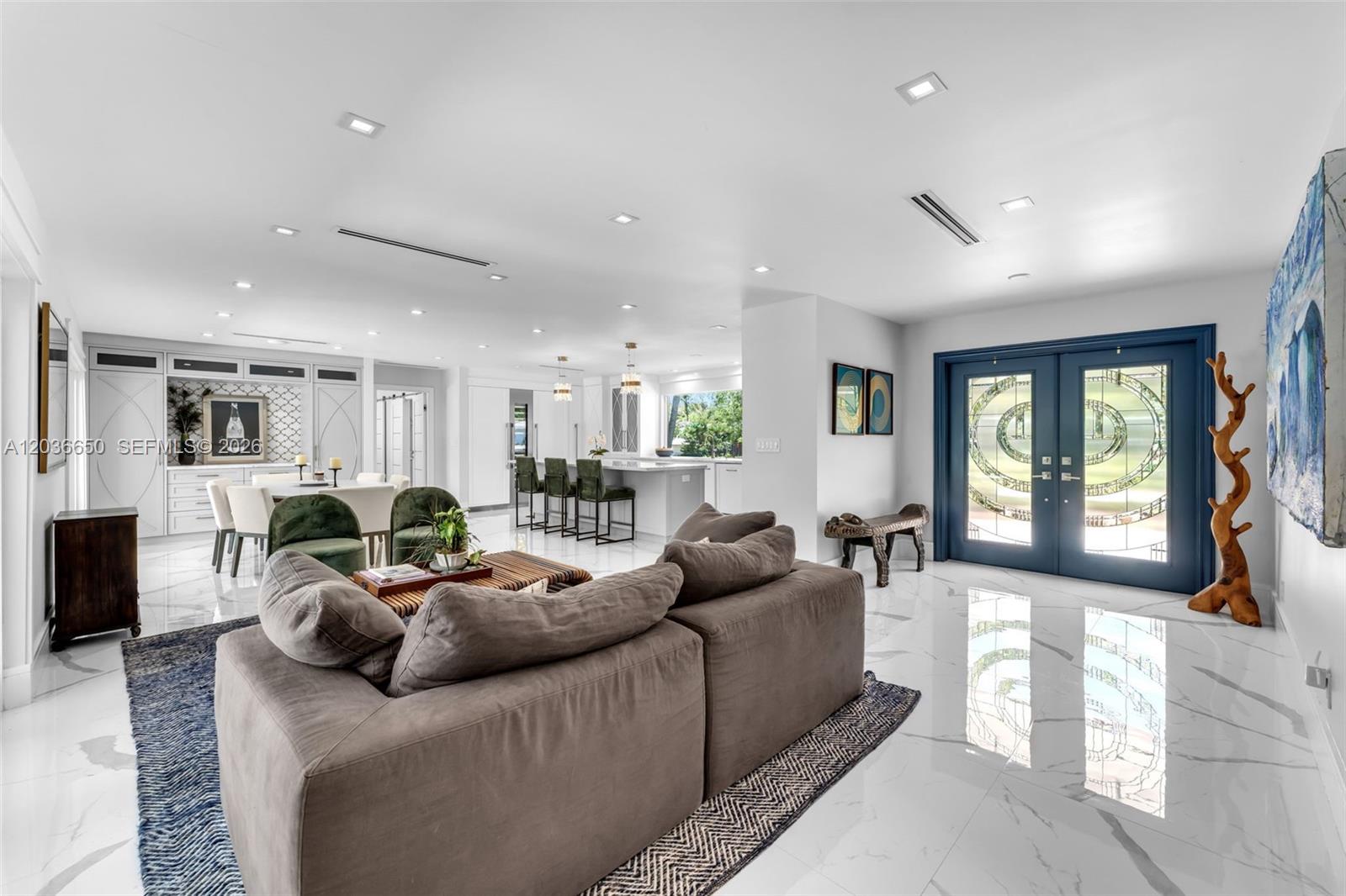 A modern open-concept living and dining area features white marble floors and blue double doors — 6561 Marlin Dr, Coral Gables FL 33158, CORAL GABLES, FL