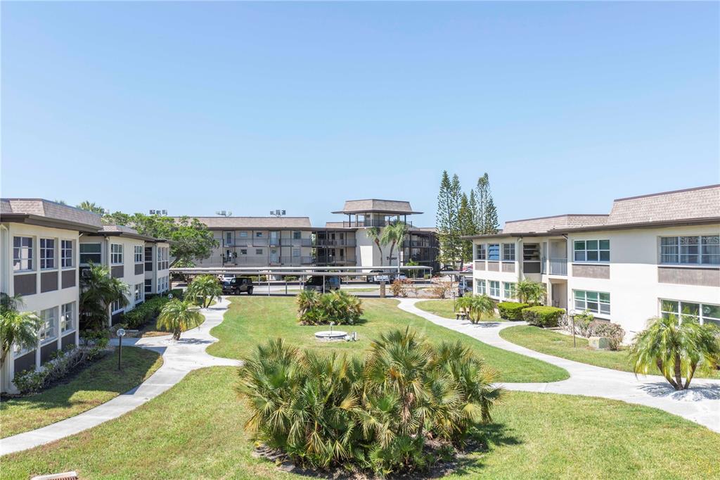 An exterior view of a multi-story apartment complex with a central courtyard and palm trees — 4726 MARINE PARKWAY UNIT 201, NEW PORT RICHEY, FL