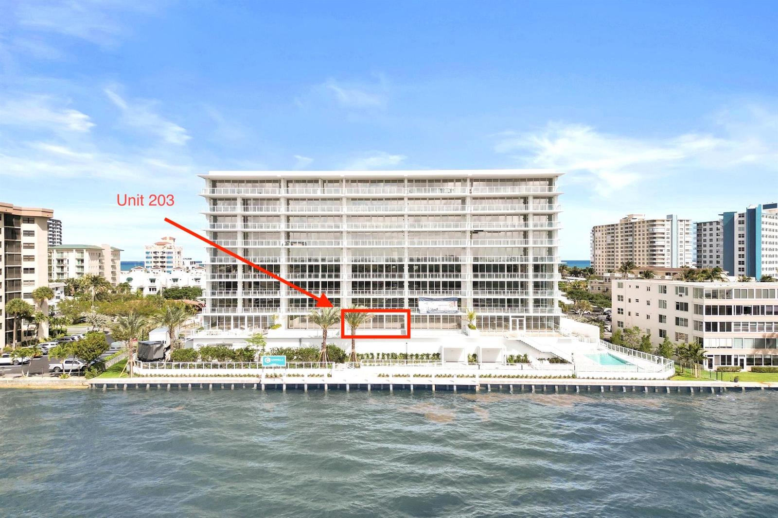 An exterior view of a waterfront residential building with a red arrow pointing to Unit 203 — 407 N Riverside Drive # 203, Pompano Beach FL 33062, POMPANO BEACH, FL