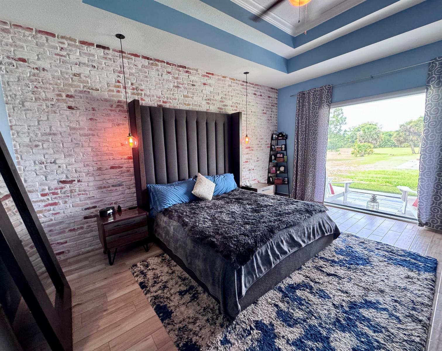 A bedroom features a tall upholstered headboard against a white brick wall and blue accents — 19008 Marsh Hawk Lane, Loxahatchee FL 33470, LOXAHATCHEE, FL