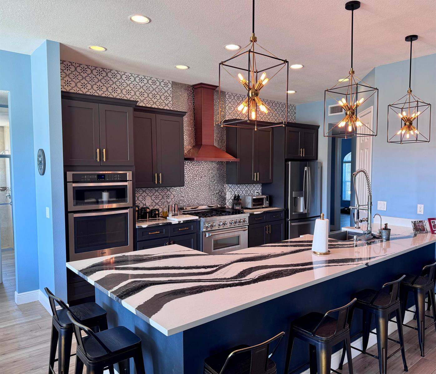 A kitchen features dark cabinets, a bold zebra-patterned island countertop, and three geometric pendant lights — 19008 Marsh Hawk Lane, Loxahatchee FL 33470, LOXAHATCHEE, FL