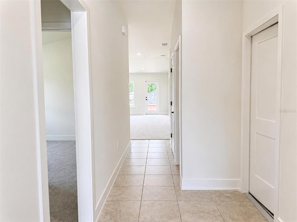 A tiled hallway leads to a carpeted room with a glass door to the outside — 250 VERNY GROVE LANE, LEESBURG, FL