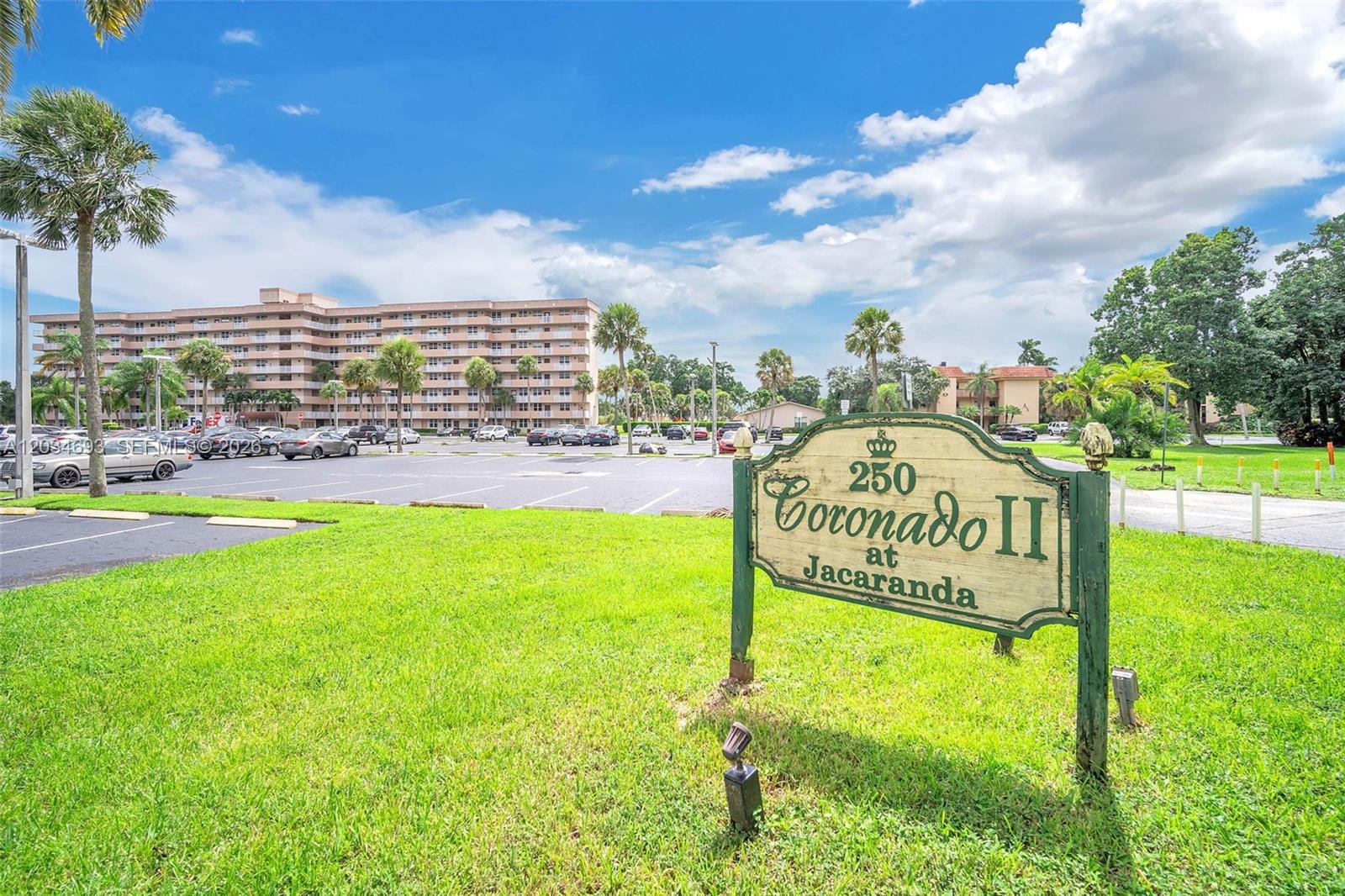 A green sign for Coronado II at Jacaranda stands in front of a large apartment building — 250 Jacaranda Dr # 704, Plantation FL 33324, PLANTATION, FL